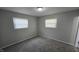 An empty bedroom with neutral walls, carpet flooring, and two windows offers a blank canvas for personalization at 5635 W Henry St, Indianapolis, IN 46241