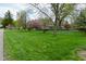 Expansive front yard with a chain-link fence, lush green lawn and mature trees, providing ample outdoor space at 601 E 95Th St, Indianapolis, IN 46240