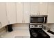 Modern kitchen featuring stainless steel microwave, black stove top, white cabinets, and light countertops at 601 E 95Th St, Indianapolis, IN 46240