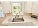 Well-lit kitchen sink featuring a stainless steel faucet, white countertops and cabinetry and a large window overlooking the backyard at 601 E 95Th St, Indianapolis, IN 46240