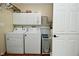 Functional laundry room with white washer and dryer units, overhead storage, and tiled flooring at 601 E 95Th St, Indianapolis, IN 46240