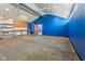 An unfinished basement offers storage and potential with blue accent wall and work area at 7104 Combs Rd, Indianapolis, IN 46237