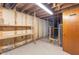 Unfinished basement with wooden storage shelving and a door to an additional room at 7104 Combs Rd, Indianapolis, IN 46237