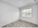 Bright, minimal bedroom featuring light wood floors, a large window, and neutral walls, perfect for relaxation at 7265 Governors Row, Avon, IN 46123