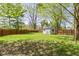 Fenced backyard boasting lush green grass, mature trees, and a charming storage shed at 8218 San Carlos Ct, Indianapolis, IN 46256
