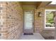 Close-up of a brick front porch with storm door, brick detail, and front door light fixture at 8218 San Carlos Ct, Indianapolis, IN 46256