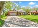 A brick ranch home with a two-car garage features a concrete driveway and mature trees at 8218 San Carlos Ct, Indianapolis, IN 46256