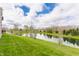 Scenic backyard with lush green grass and a tranquil pond reflecting the blue sky and fluffy clouds at 8330 Dumfries Dr, Brownsburg, IN 46112