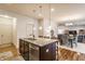 Open-concept kitchen island with seating, sink, and stainless steel dishwasher, seamlessly connected to the dining area at 8330 Dumfries Dr, Brownsburg, IN 46112