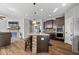 The open-concept kitchen features dark cabinetry, stainless steel appliances, a center island, and pendant lighting at 957 Commander Ct, Westfield, IN 46074