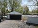 View of a detached garage with black door and a shed behind with white fence at 1029 Price Rd, Avon, IN 46123