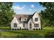 Charming white brick home with a gray roof, surrounded by lush landscaping and mature trees at 10415 Westfield Blvd, Carmel, IN 46280