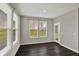 Bright sun room with hardwood floors and three large windows and a door that leads to the backyard at 10423 Hamburg Dr, Fortville, IN 46040