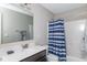 Neutral bathroom featuring a single sink vanity, full mirror, and a tub/shower combo with a blue shower curtain at 10810 Arendale Dr, Brownsburg, IN 46112