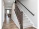 Staircase with carpet and dark wood railing adjacent to a spacious hall with recreational space beyond at 10810 Arendale Dr, Brownsburg, IN 46112