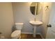 Cozy half bathroom featuring a pedestal sink, toilet, and round mirror at 1114 Ridgevine Rd, Greenwood, IN 46143