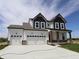 Two-story home showcasing a three-car garage and stylish black and white color scheme at 1114 Ridgevine Rd, Greenwood, IN 46143