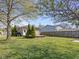 Backyard with a wooden deck, neutral siding, green grass, small evergreen trees, and a wood fence at 125 W Noble St, Lebanon, IN 46052
