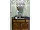 Bathroom vanity featuring a black granite countertop, wood cabinets, and decorative mirror at 12867 Andover Dr, Carmel, IN 46033