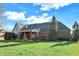 Expansive backyard with lush green grass and brick home exterior and covered cedar porch at 16 Cattail Ln, Brownsburg, IN 46112