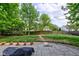 Large backyard with a stone patio, mature trees, and a fenced perimeter at 18980 Bladed Mills Dr, Noblesville, IN 46062
