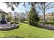 Spacious backyard with green grass, mature trees, stone flower beds, and a patio area at 19311 Morrison Way, Noblesville, IN 46060