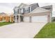 Two-story home featuring a two-car garage, grey vinyl siding, and well-manicured green lawn at 210 Aster Way, Greenfield, IN 46140