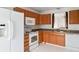 Functional kitchen featuring wood cabinets, white appliances, and durable tile flooring at 2138 Rossington Ln, Indianapolis, IN 46229