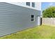 Side exterior featuring gray siding, a white door, window and well-maintained lawn at 2302 Prospect St, Indianapolis, IN 46203