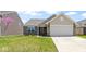 Charming home featuring a well-manicured lawn, brick accents, a two-car garage, and a delightful splash of color from a flowering tree at 2427 Apple Tree Ln, Indianapolis, IN 46229
