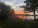 Beautiful sunset view from the waterfront backyard, featuring a well-maintained lawn and a private dock with chairs at 2428 Hawthorn Pl, Noblesville, IN 46062