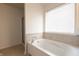 Bathroom featuring a soaking tub with tile surround and a window for natural light at 2545 Coneflower Ct, Columbus, IN 47201