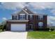 Charming two-story brick home with manicured lawn, and a two car garage under a cloudy blue sky at 2545 Coneflower Ct, Columbus, IN 47201