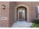 Inviting front entrance with a stylish, dark wood door and beautiful brick archway, and green landscaping at 2545 Coneflower Ct, Columbus, IN 47201