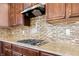 Modern cooktop set in stone countertop with decorative backsplash and wood cabinets above and below at 2545 Coneflower Ct, Columbus, IN 47201