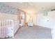 This cute bedroom features fun wallpaper, crib, chair, ceiling fan, and ample space at 3413 Putter Pl, Columbus, IN 47203
