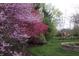 Landscaped backyard featuring a well-manicured lawn, flowering trees and a black metal fence at 3790 Steeplechase Dr, Carmel, IN 46032