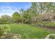 Large backyard featuring a well-kept lawn, mature trees, and meticulously arranged flower beds at 3790 Steeplechase Dr, Carmel, IN 46032