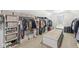 Spacious walk-in closet with custom shelving, clothing racks, central bench, and natural light from the window at 3790 Steeplechase Dr, Carmel, IN 46032