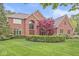 Beautiful brick home featuring a manicured lawn, mature trees, and a circular garden in the front yard at 3790 Steeplechase Dr, Carmel, IN 46032