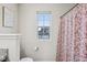 A light and airy bathroom with a red floral shower curtain and a window with a view of other houses at 4245 W Fork Dr, Westfield, IN 46062