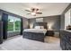A dark bedroom featuring a large bed, a ceiling fan with lights, two bedside tables, and a window with green trees outside at 4245 W Fork Dr, Westfield, IN 46062