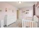 A delightful Bedroom with pink walls, showcasing a crib and changing table ready for a new arrival at 4245 W Fork Dr, Westfield, IN 46062