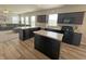 A modern kitchen with dark cabinets, granite countertops, stainless steel appliances, and wood-look flooring provides modern elegance at 4245 W Fork Dr, Westfield, IN 46062