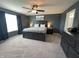 A cozy primary bedroom with a large bed, dark wood furniture, neutral carpet, ceiling fan and large window at 4245 W Fork Dr, Westfield, IN 46062