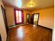 Bedroom with hardwood floors, large window with sheer curtain, and views into adjoining rooms at 4335 River Rd, Columbus, IN 47203