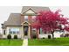 Charming two-story home featuring a brick facade, well-manicured lawn, and a beautiful flowering tree in full bloom at 5266 Hickory Lake Dr, Indianapolis, IN 46235