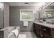 Detailed bathroom featuring dual sinks, a tub, walk-in shower and gray tile at 5467 Winterhazel Dr, Indianapolis, IN 46254