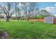 Large green backyard with mature trees, wooden fence, storage shed, and bench at 600 Alexandria Pike, Anderson, IN 46012