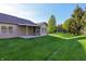 Lush backyard featuring a covered patio, mature trees, and manicured green lawn at 6017 Riva Ridge Dr, Indianapolis, IN 46237